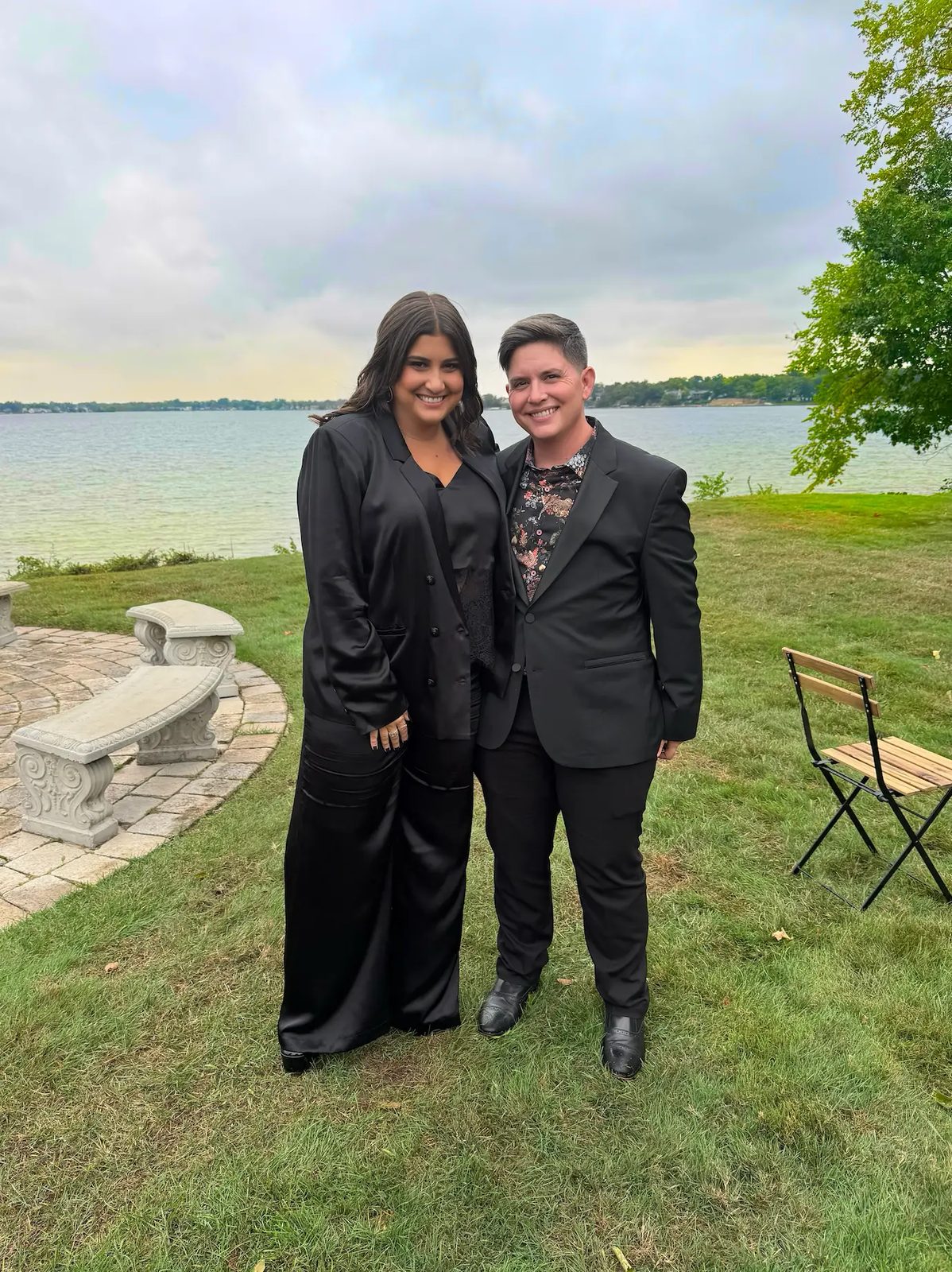 Ashley and Eli in formal black outfits beside a lake